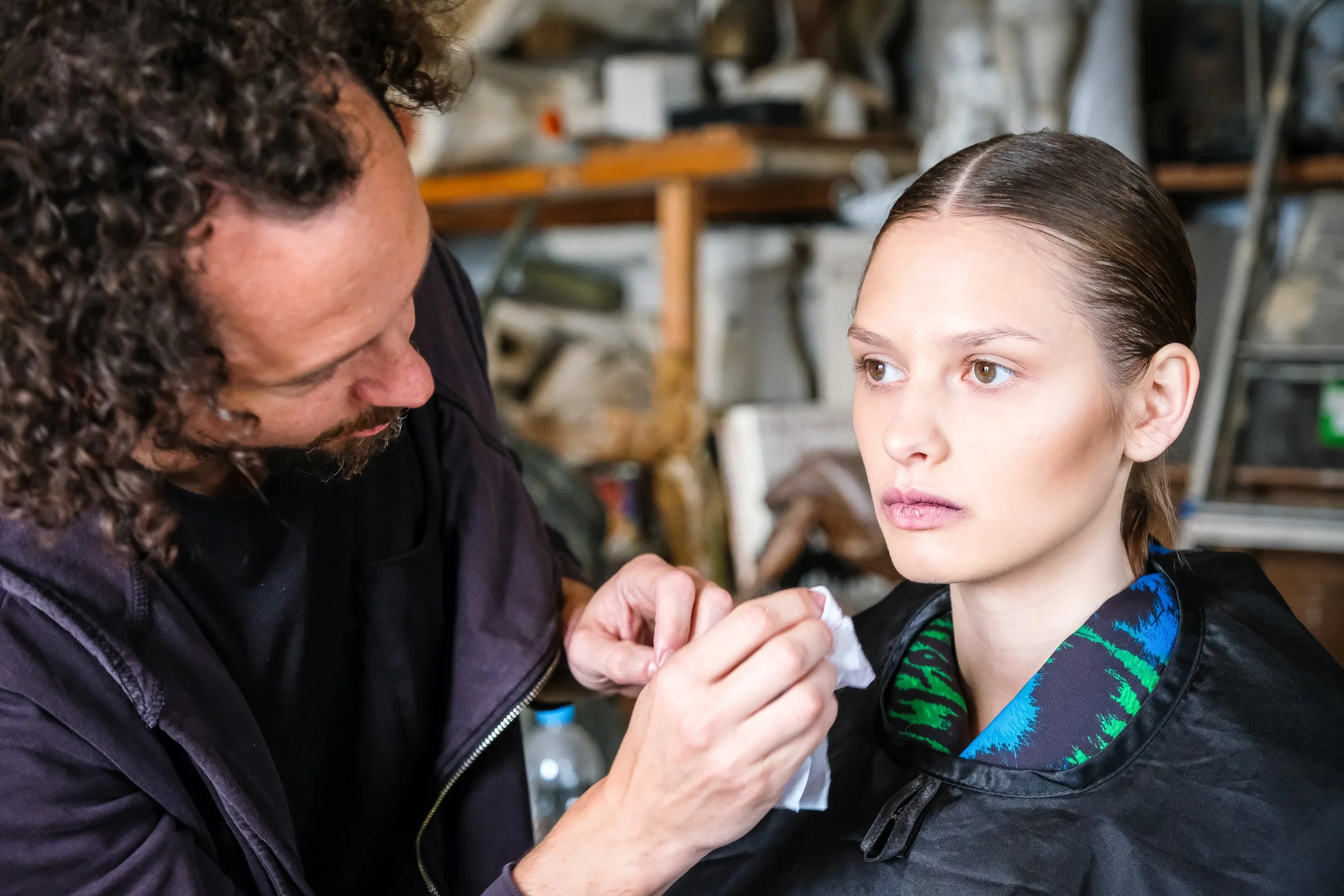 Ein Mann macht einem Mädchen im Atelier mit Pinsel und Tuch Make-up.