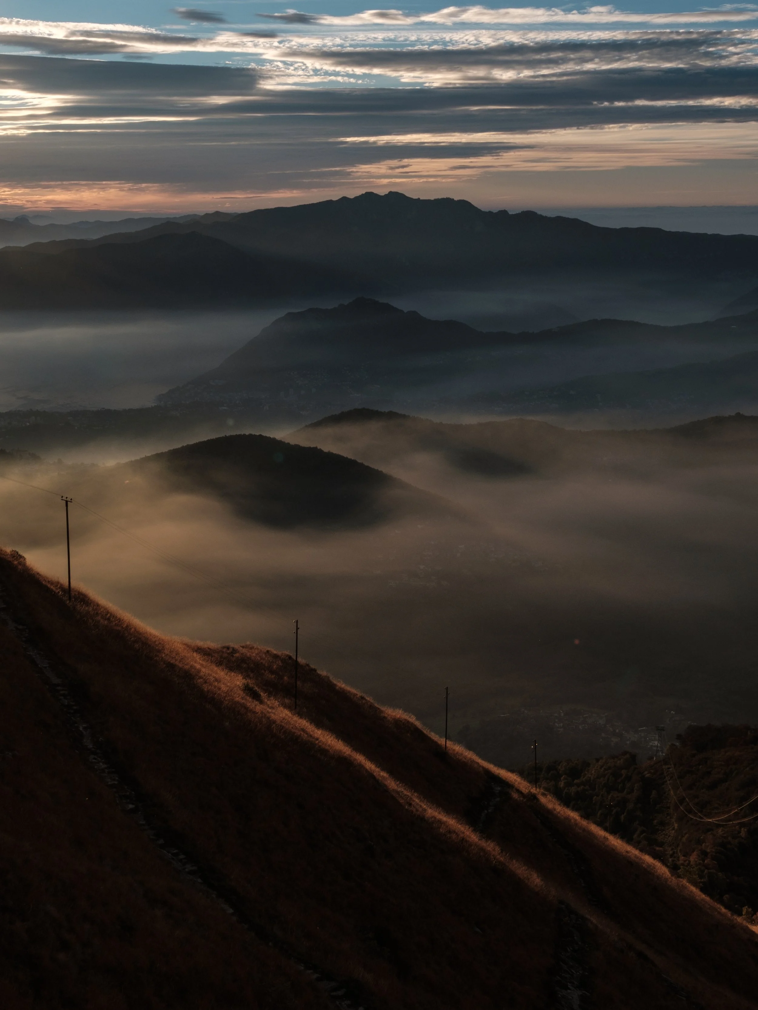 Berglandschaft bei Sonnenaufgang mit Nebel und Wolken am Himmel.