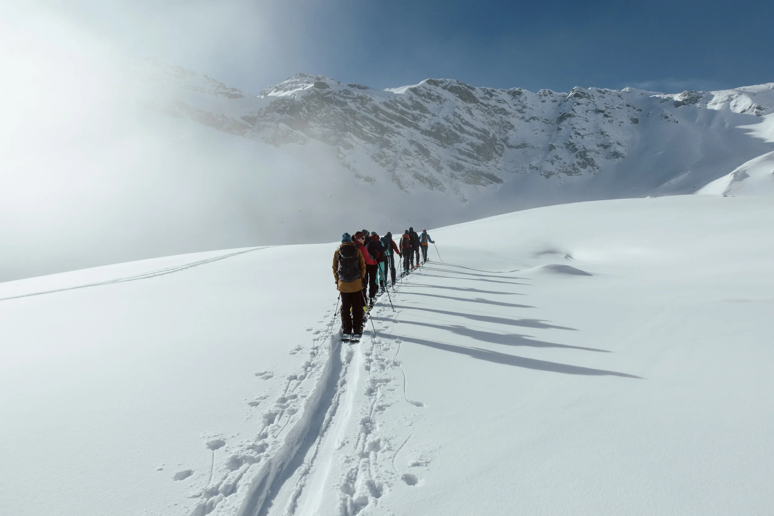 Grupp von Skifahrern in verschneiter Berglandschaft bei sonnigem Himmel