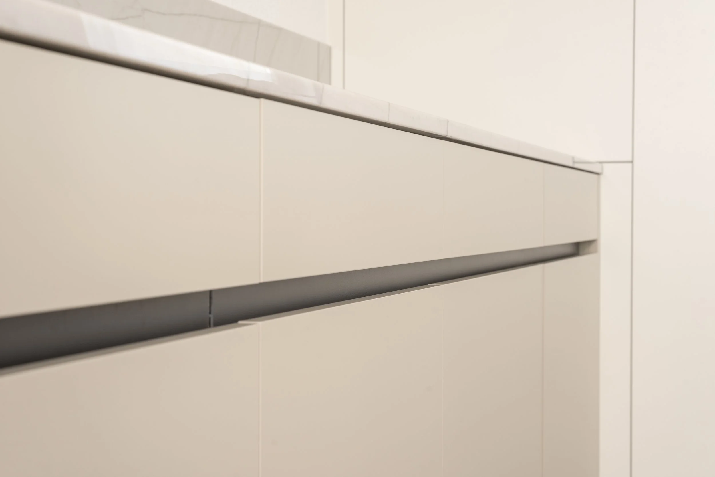 Nahaufnahme einer modernen weißen Küchenschublade mit einem schmalen Spalt zwischen den Schubladen
