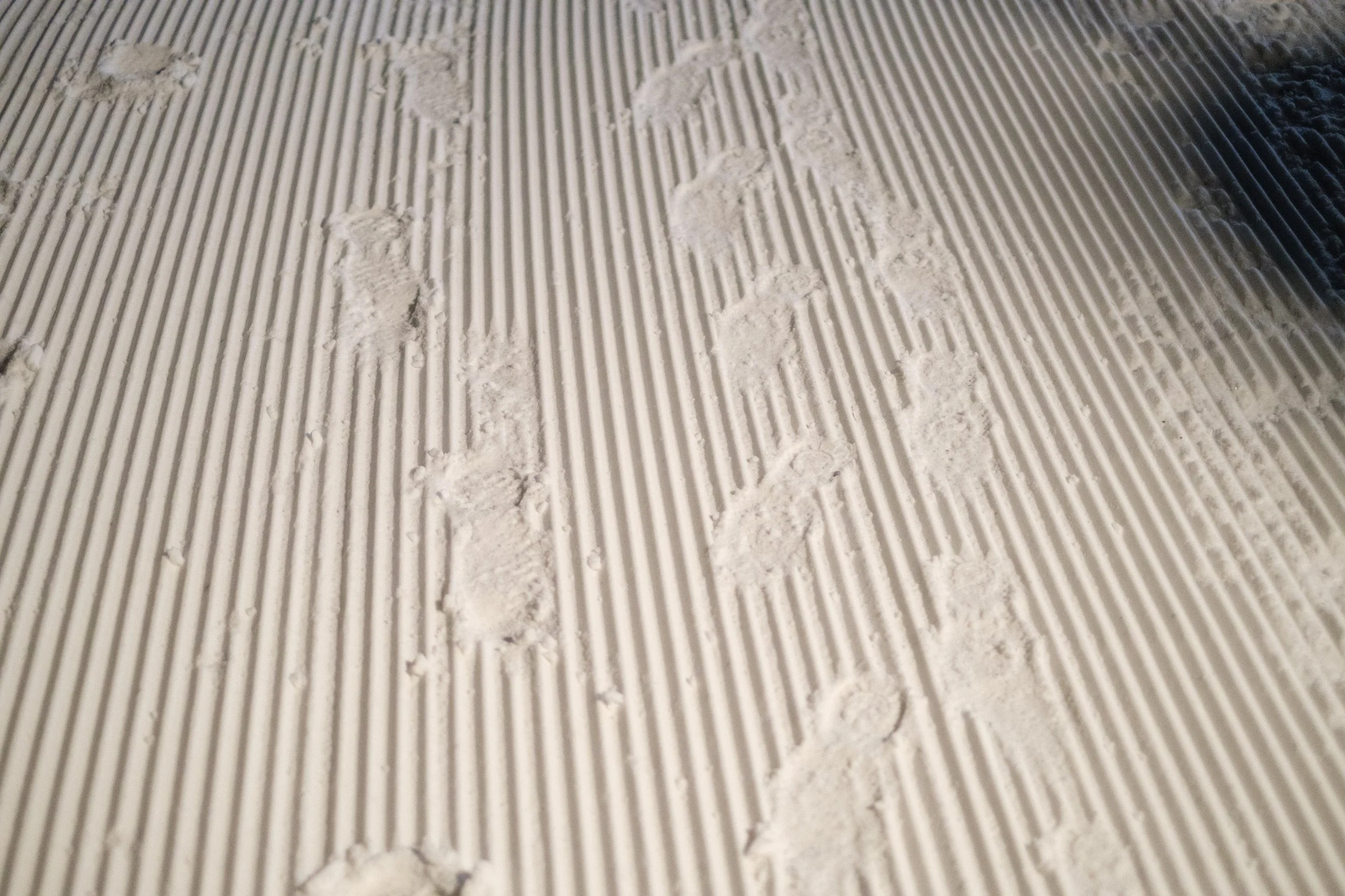 Fußabdrücke im Schneestrand mit gerilltem Muster.