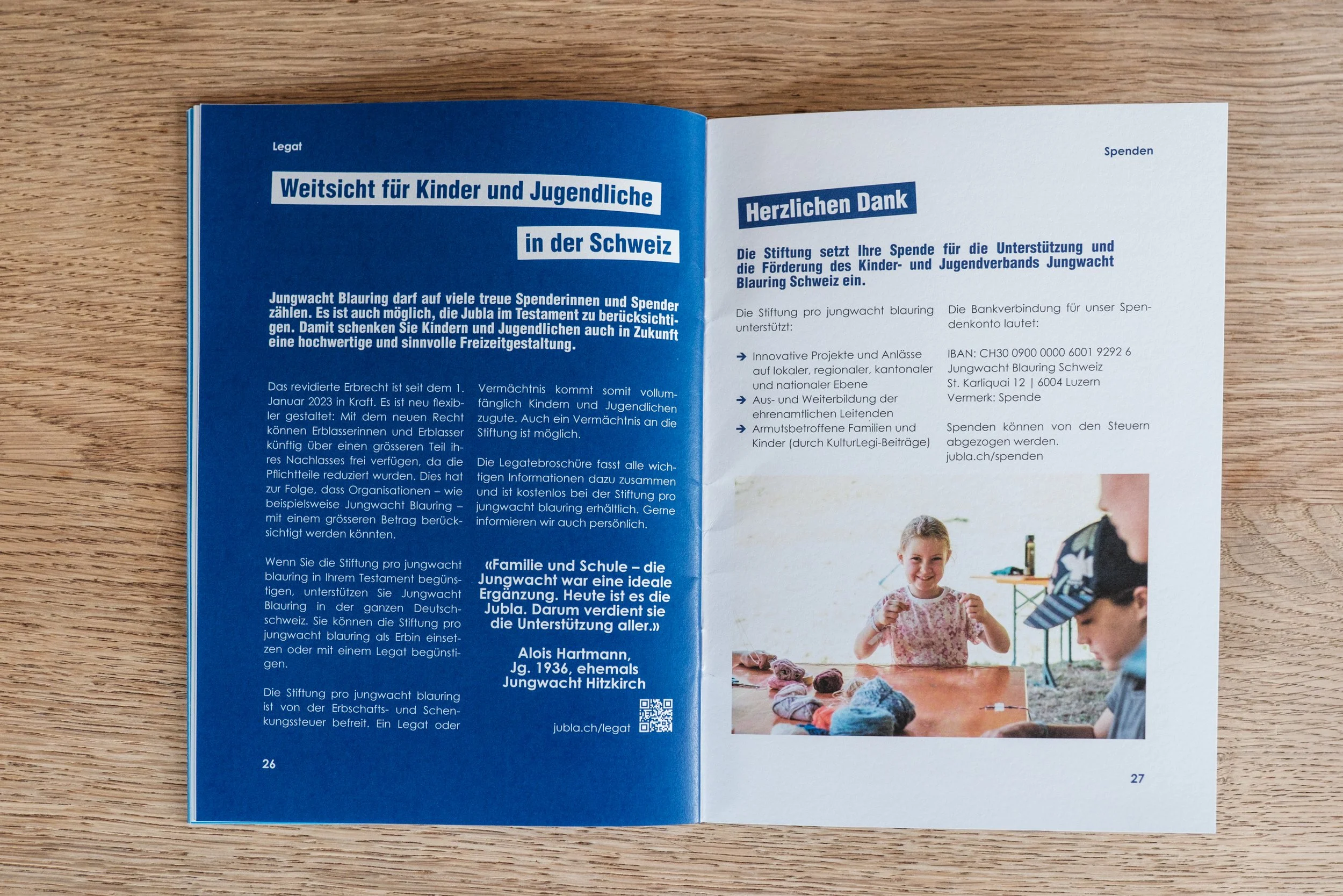 Offen geblättertes Magazin auf Holzoberfläche, Doppelseite mit Text über Kinder- und Jugendwohlfahrt in der Schweiz und eine Fotografie von drei Kindern am Tisch, lachend und spielend.