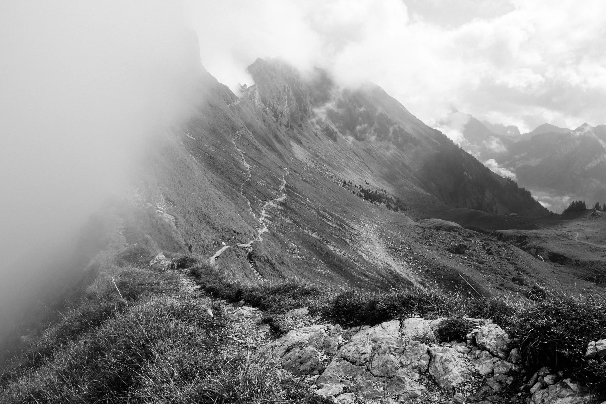 Wanderweg in den Bergen mit nebligem Himmel und grippeverdächtiger Landschaft in Schwarz-Weiß